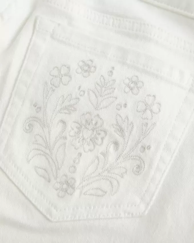Jeans a zampa con tasche ricamate bianche a vita bassissima