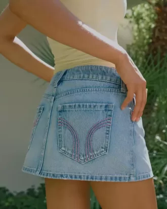 Mini gonna-pantalone in denim chiaro ricamato rosa a vita bassa
