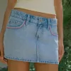 Mini gonna-pantalone in denim chiaro ricamato rosa a vita bassa