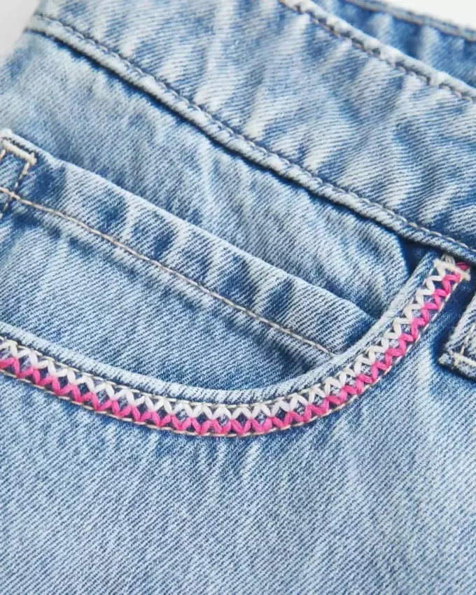 Mini gonna-pantalone in denim chiaro ricamato rosa a vita bassa