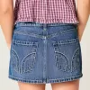 Mini gonna-pantalone in denim con borchie a vita bassa