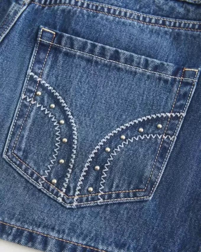 Mini gonna-pantalone in denim con borchie a vita bassa