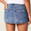 Mini gonna-pantalone in denim con fiocco ricamato a vita bassa e sinuosa