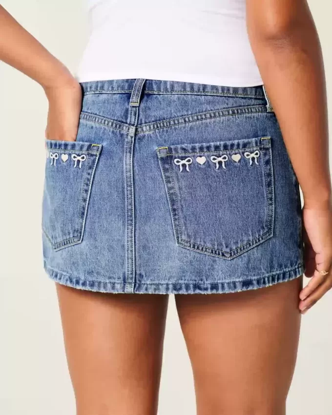 Mini gonna-pantalone in denim con fiocco ricamato a vita bassa e sinuosa