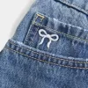 Mini gonna-pantalone in denim con fiocco ricamato a vita bassa e sinuosa