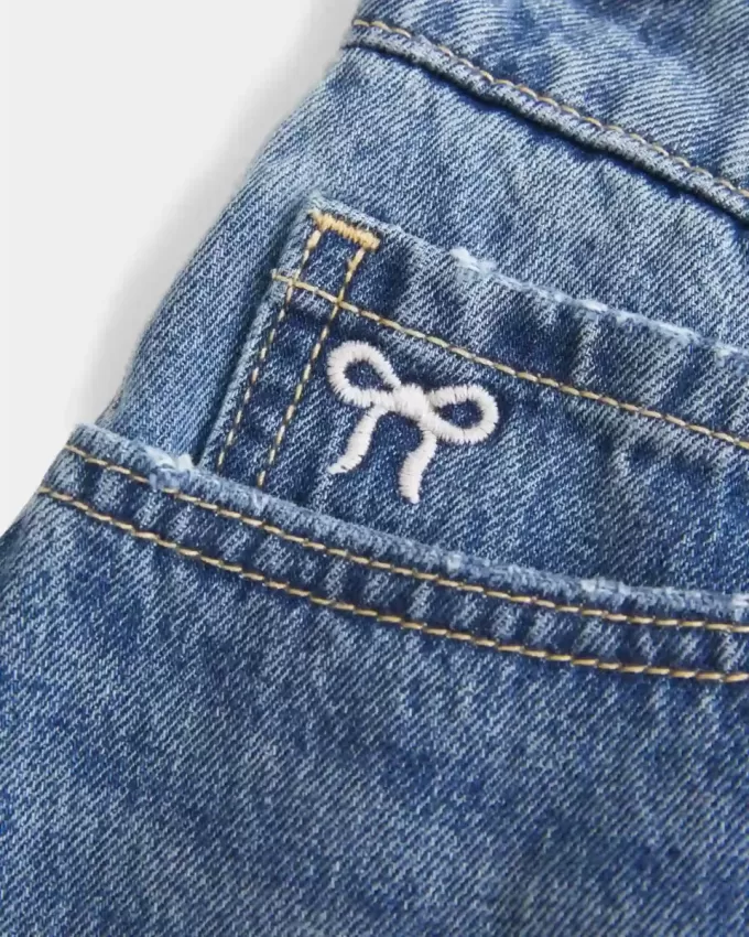 Mini gonna-pantalone in denim con fiocco ricamato a vita bassa e sinuosa
