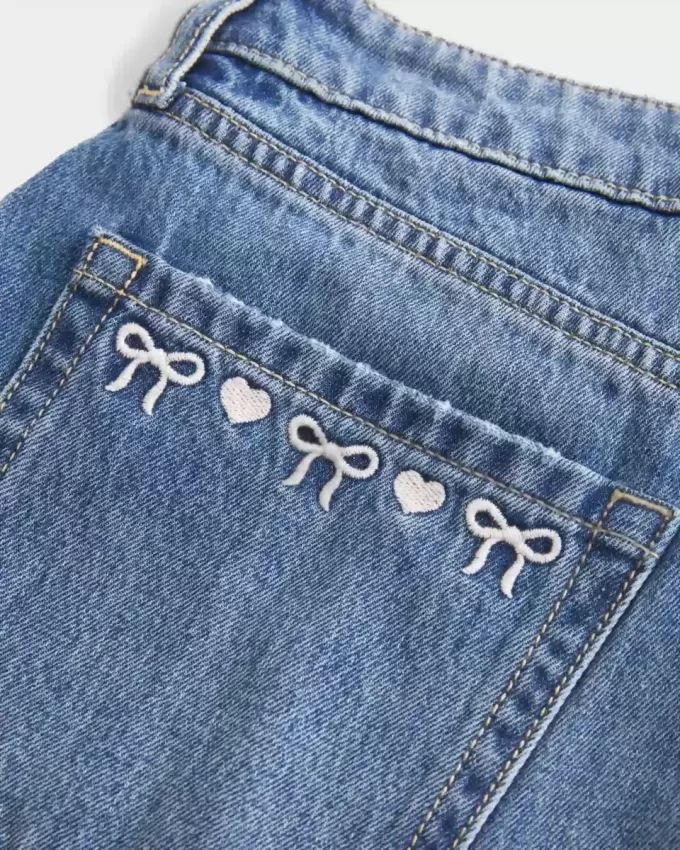 Mini gonna-pantalone in denim con fiocco ricamato a vita bassa e sinuosa